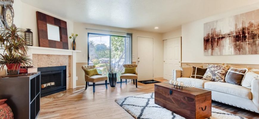 large and modern living room with a fireplace to the far left, a rug to the right with a chest on top.